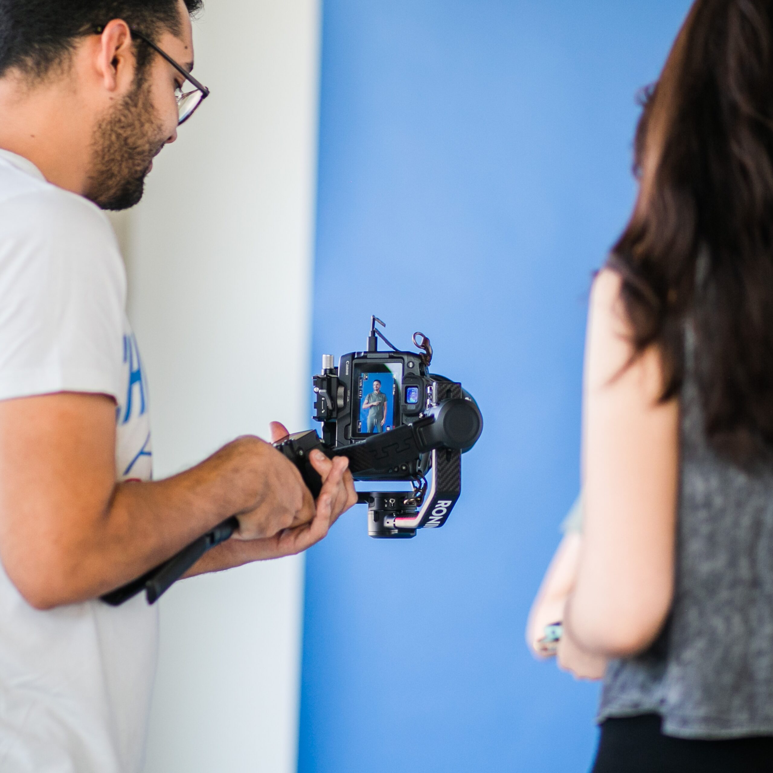 Two people filming indoors using a professional camera setup, focusing on videography.